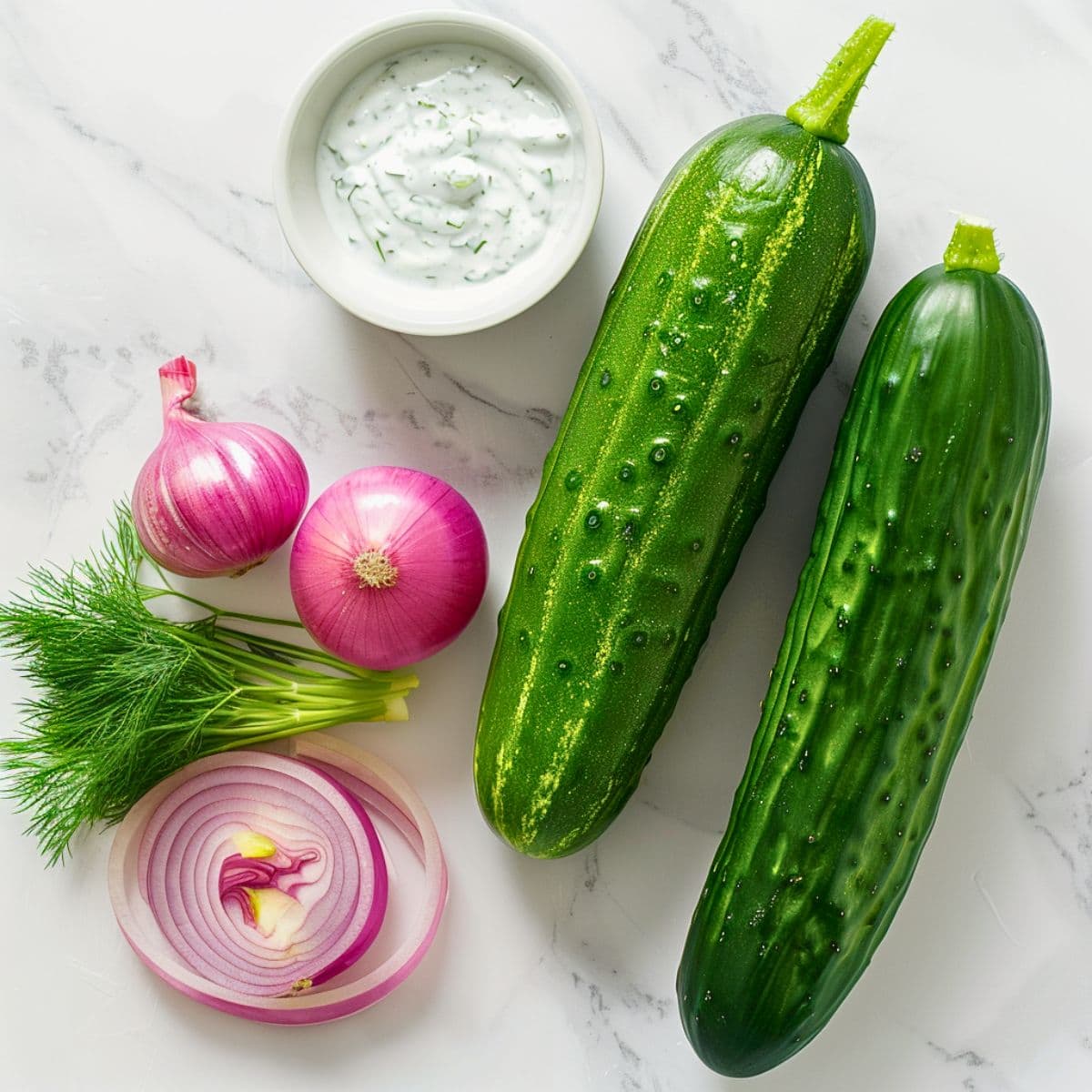 Cucumbers, red onions, dills and dressing on a white marble table. 