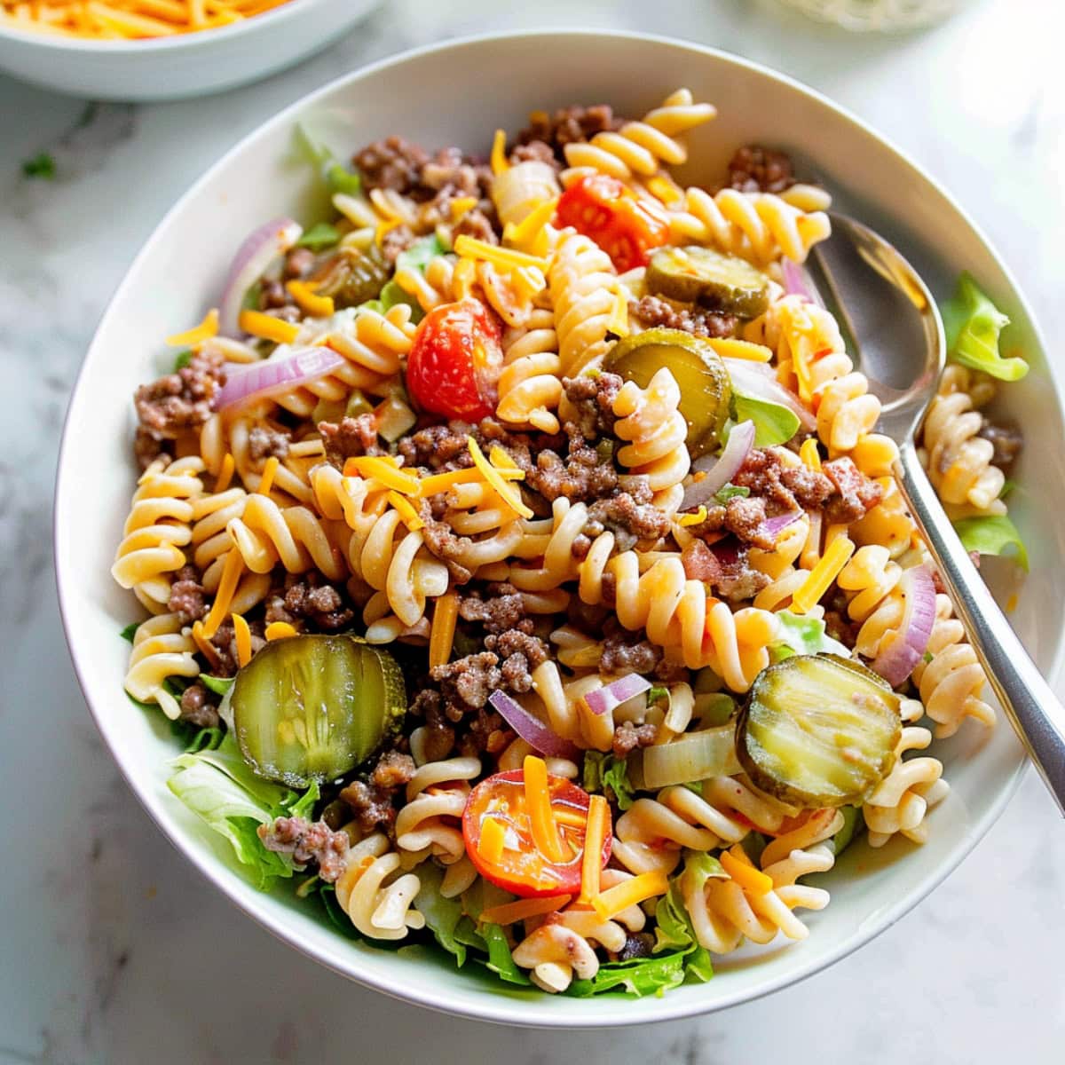 Cheeseburger inspired Jimmy Buffett pasta salad with ground beef, red onions and cherry tomatoes.