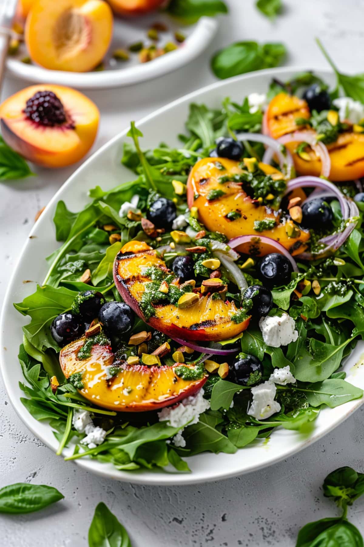 A platter of grilled peach salad topped with nuts, berries, onions, cheese, and basil dressing. 