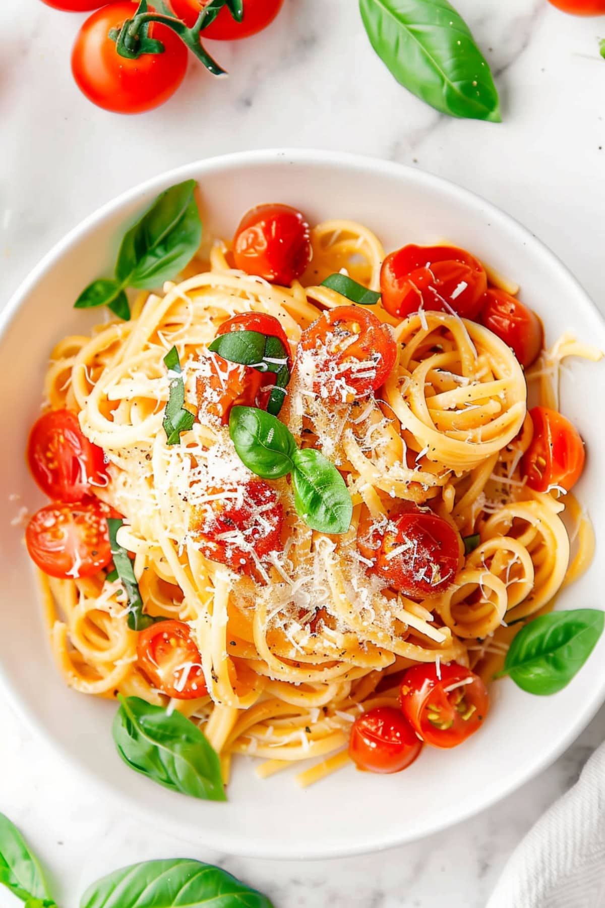 Homemade cherry tomato and basil pasta with parmesan cheese and basil in a bowl.