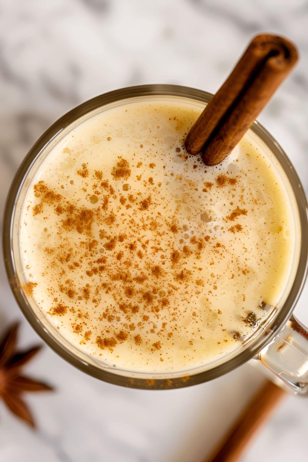 Super Close Top View of Hot Buttered Rum in a Glass with a Dusting of Cinnamon, Garnished with a Cinnamon Stick