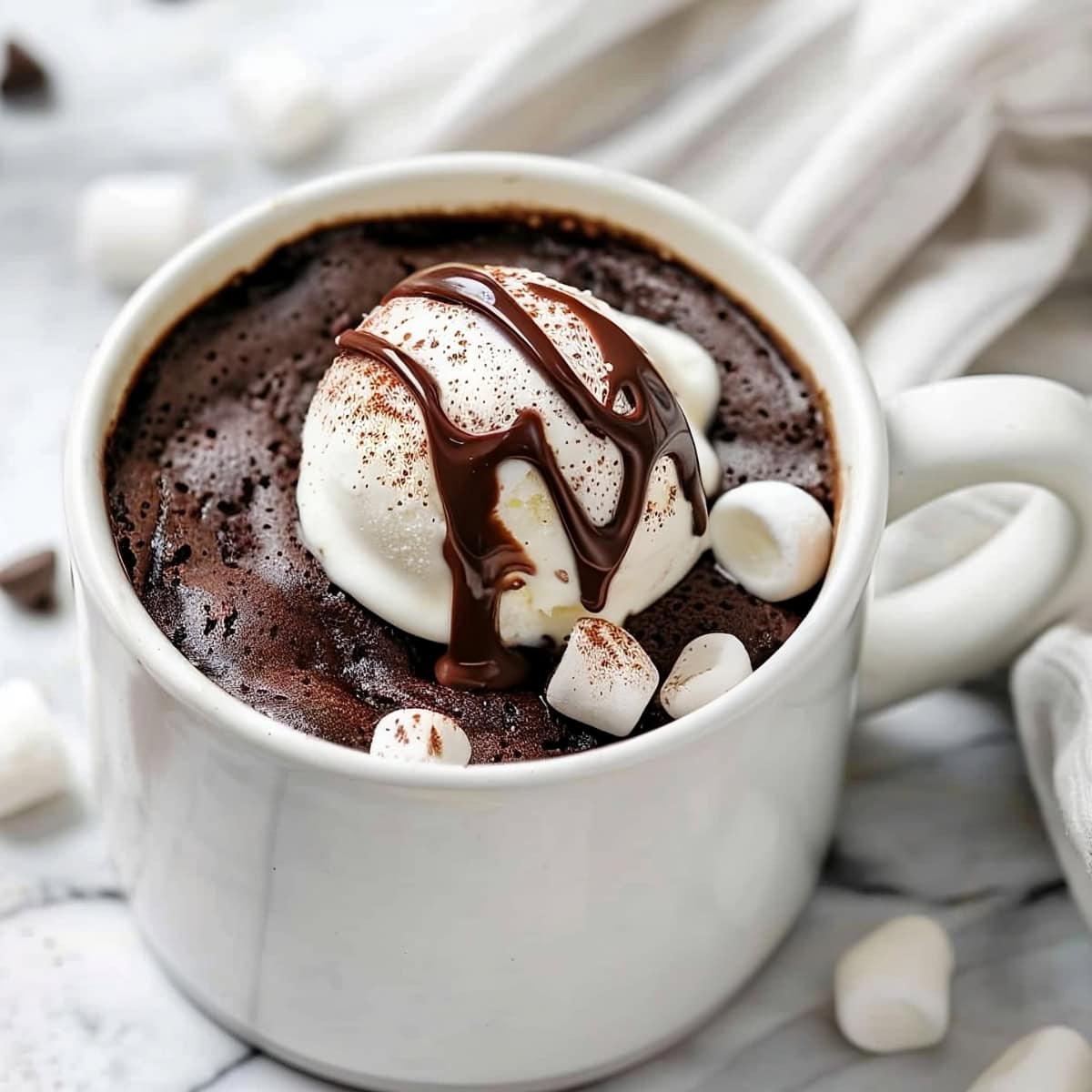 Hot chocolate mug cake with a scoop of vanilla ice cream, marshmallows and chocolate sauce.