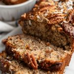 Close Up of Jamaican Banana Bread Loaf and Two Slices with Toasted Coconut and Toasted Pecans