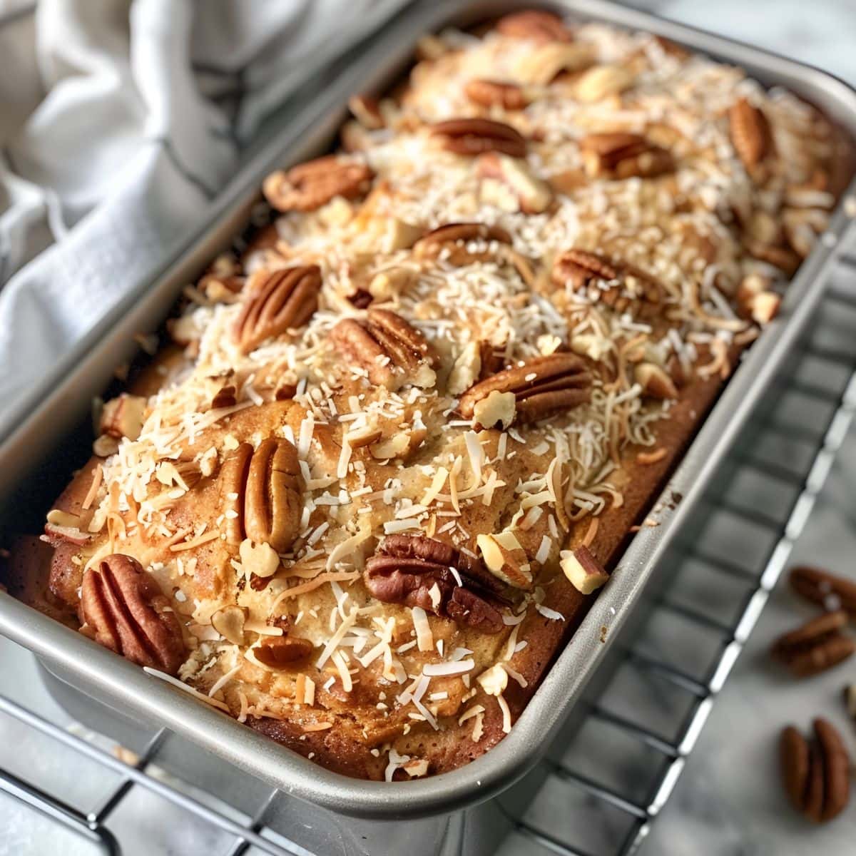 Jamaican Banana Bread with Toasted Coconut and Pecans Cooling in a Loaf Pan on a Wire Rack