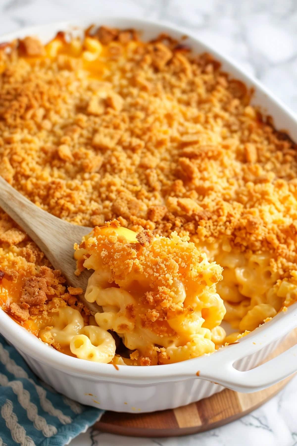 Close Up of Gooey Original Kraft Mac and Cheese with Ritz Cracker Topping in a Casserole Dish with a Wooden Spoon
