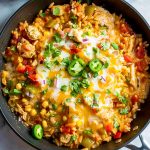 Top View of Mexican Chicken and Rice- Rice, Chicken Tomatoes, Corn, Peppers, and Cheese- In a Skillet, Topped with Fresh Jalapenos and Cilantro