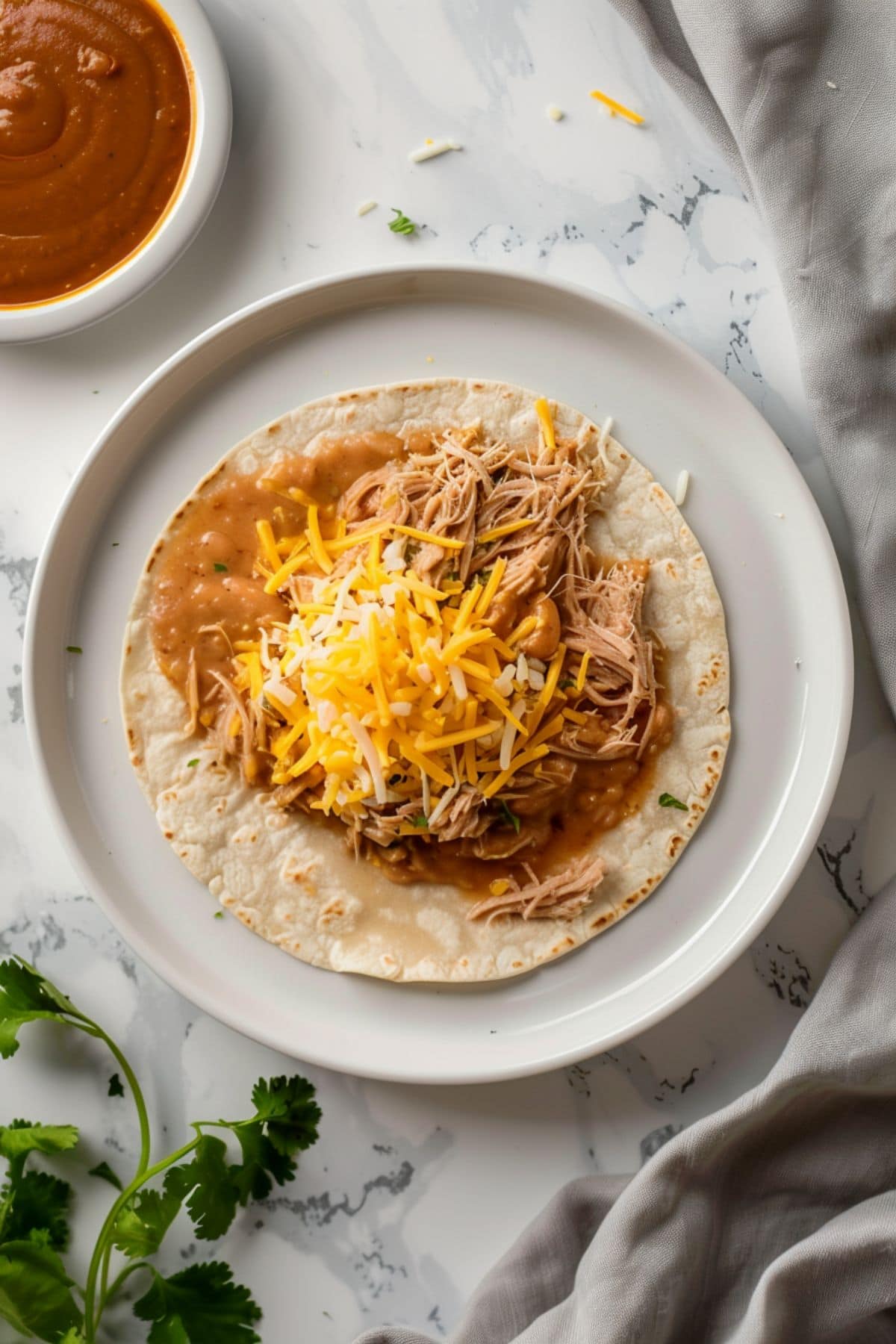 Corn tortilla topped with refried beans, pulled pork and grated cheese, enchilada sauce on the side. 