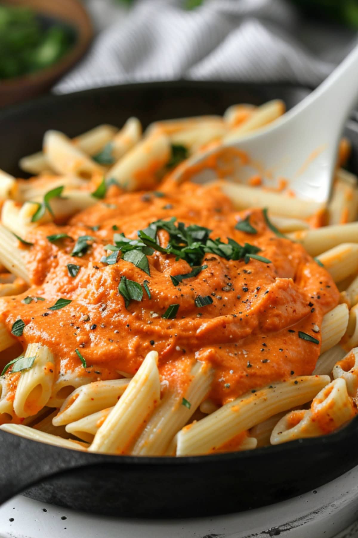 Penne pasta tossed in skillet pan with roasted red peppers puree.