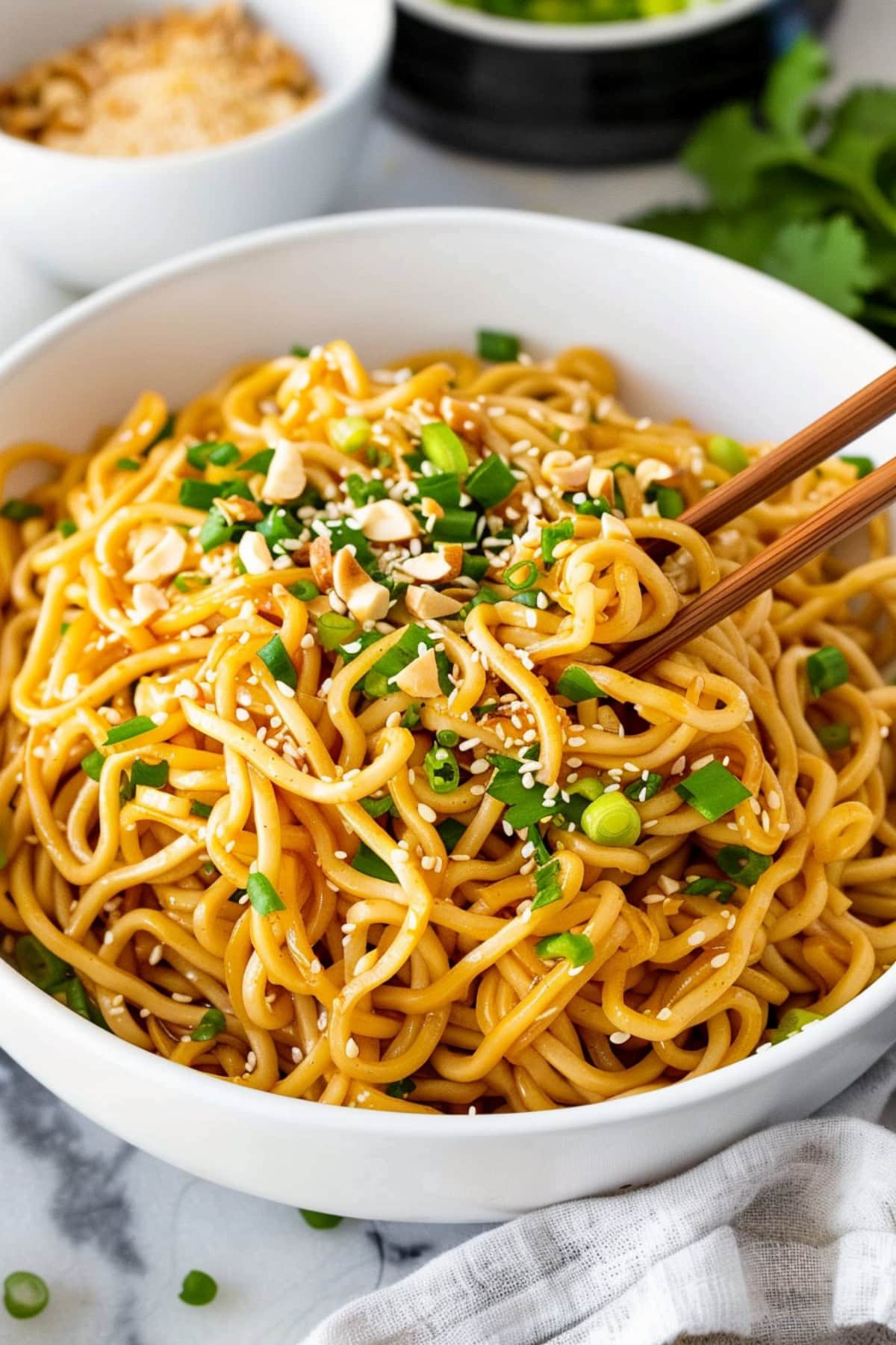 Flavorful sesame noodles with green onions and nuts in a bowl