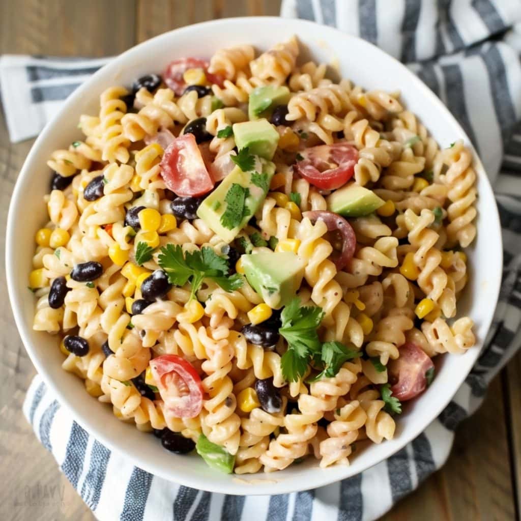 A detailed shot of Tex-Mex pasta salad on a wooden table, revealing the mix of fresh and vibrant ingredients.