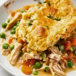 Close Up of TikTok Chicken Cobbler Pot Pie- with Meaty Chicken, Carrots, Peas, Sauce, and Flaky Biscuit- on a Plate