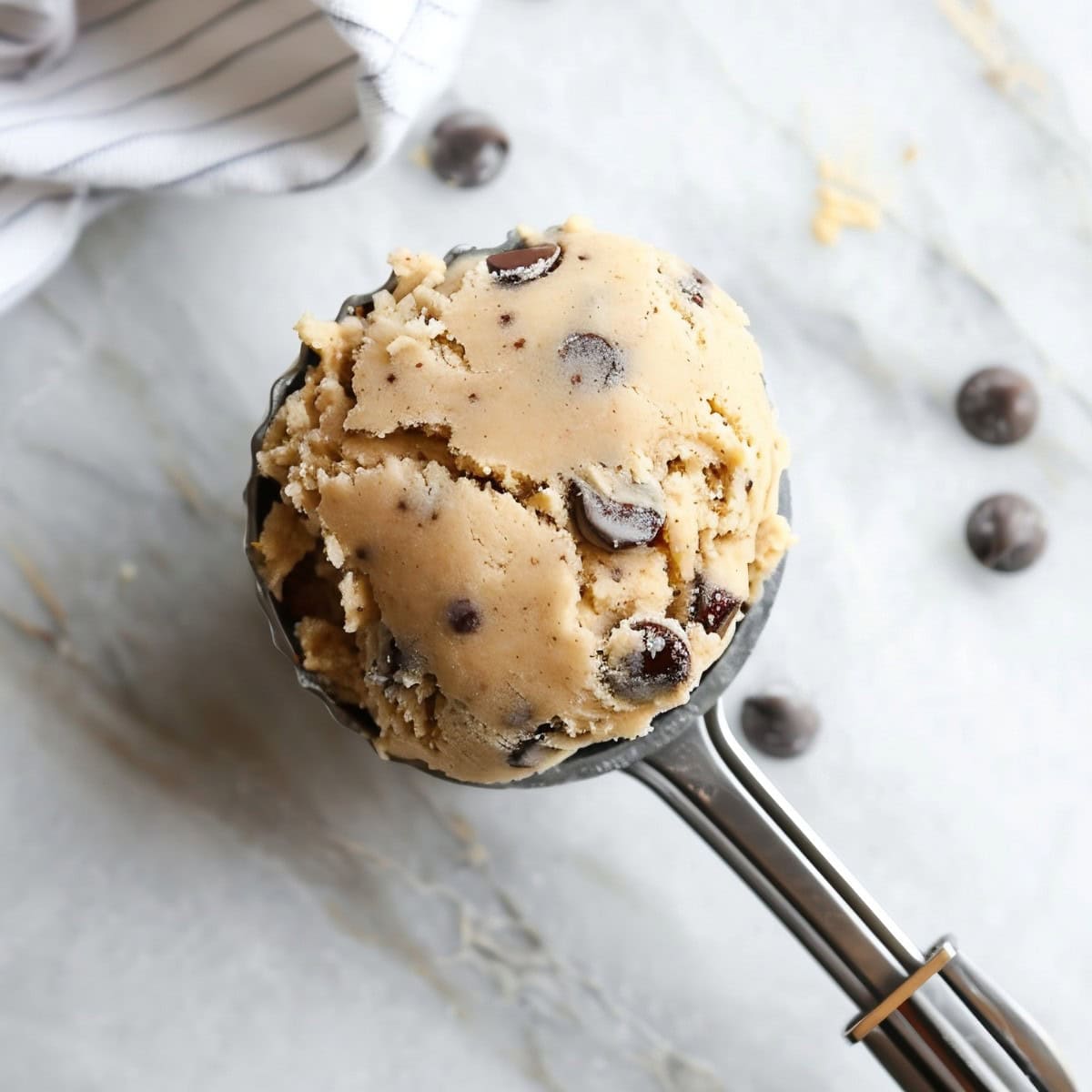 Brown Butter Chocolate Chip Cookie Dough in a Cookie Dough Scoop Over a White Marble Table
