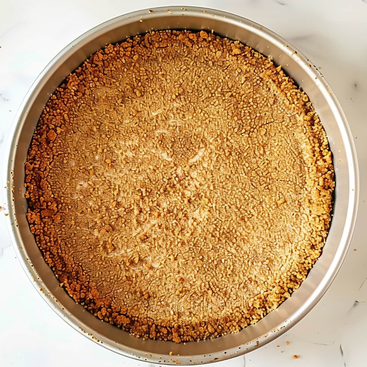 Graham cracker crumbs in a stainless container, top view.