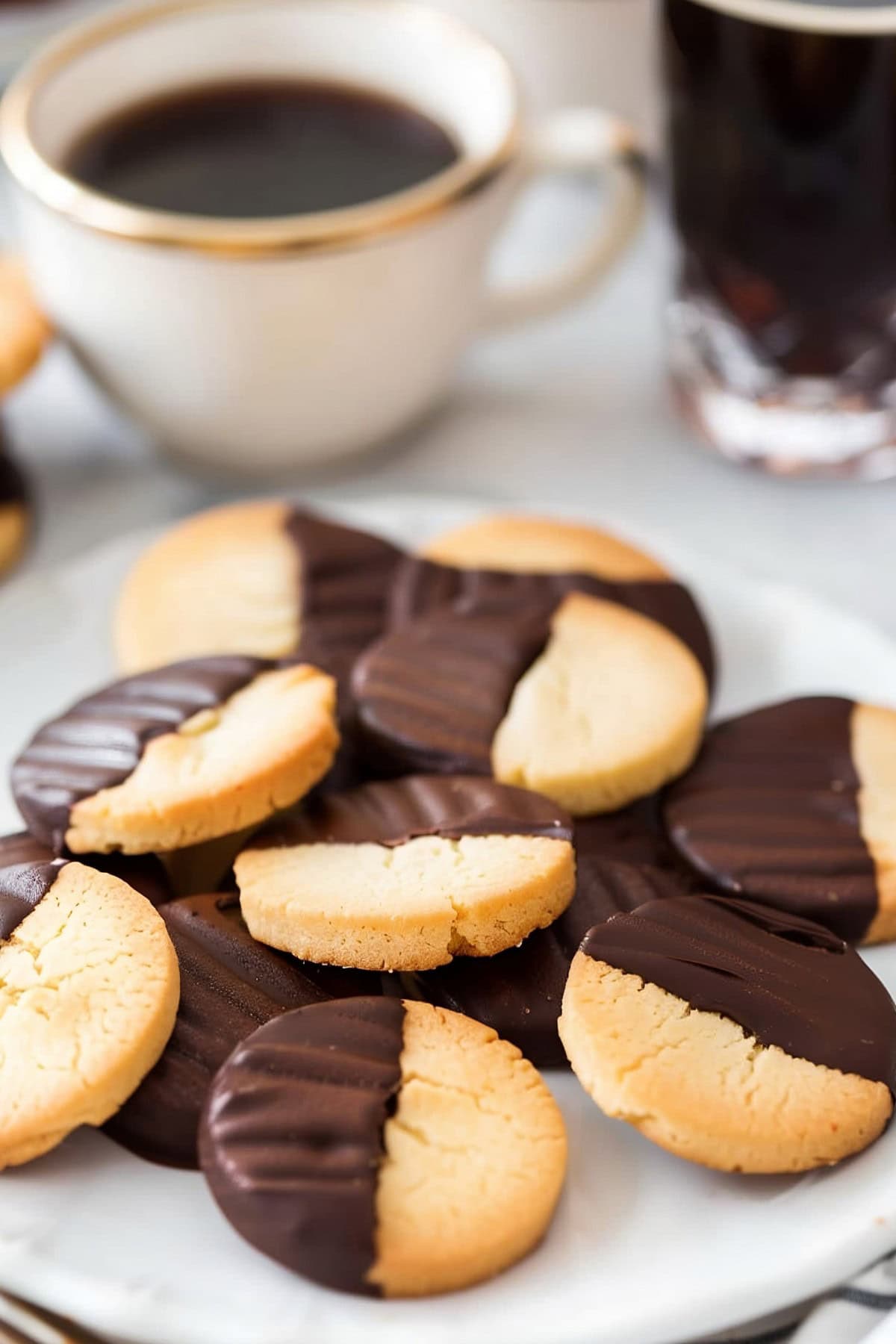 Chocolate-Dipped Shortbread Cookies on a Plate with Coffee in the Background