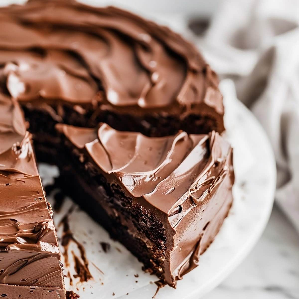 Chocolate Truffle Cake sliced, topped with chocolate frosting sitting on a cake tray.