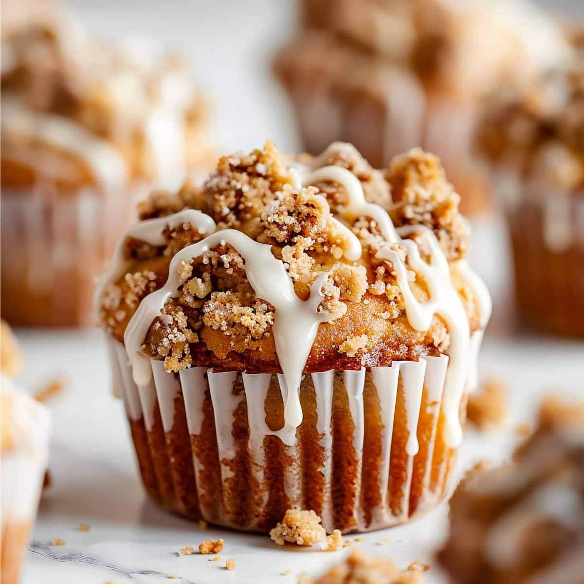 Coffee Cake Muffins drizzled with white glaze on a marble table.