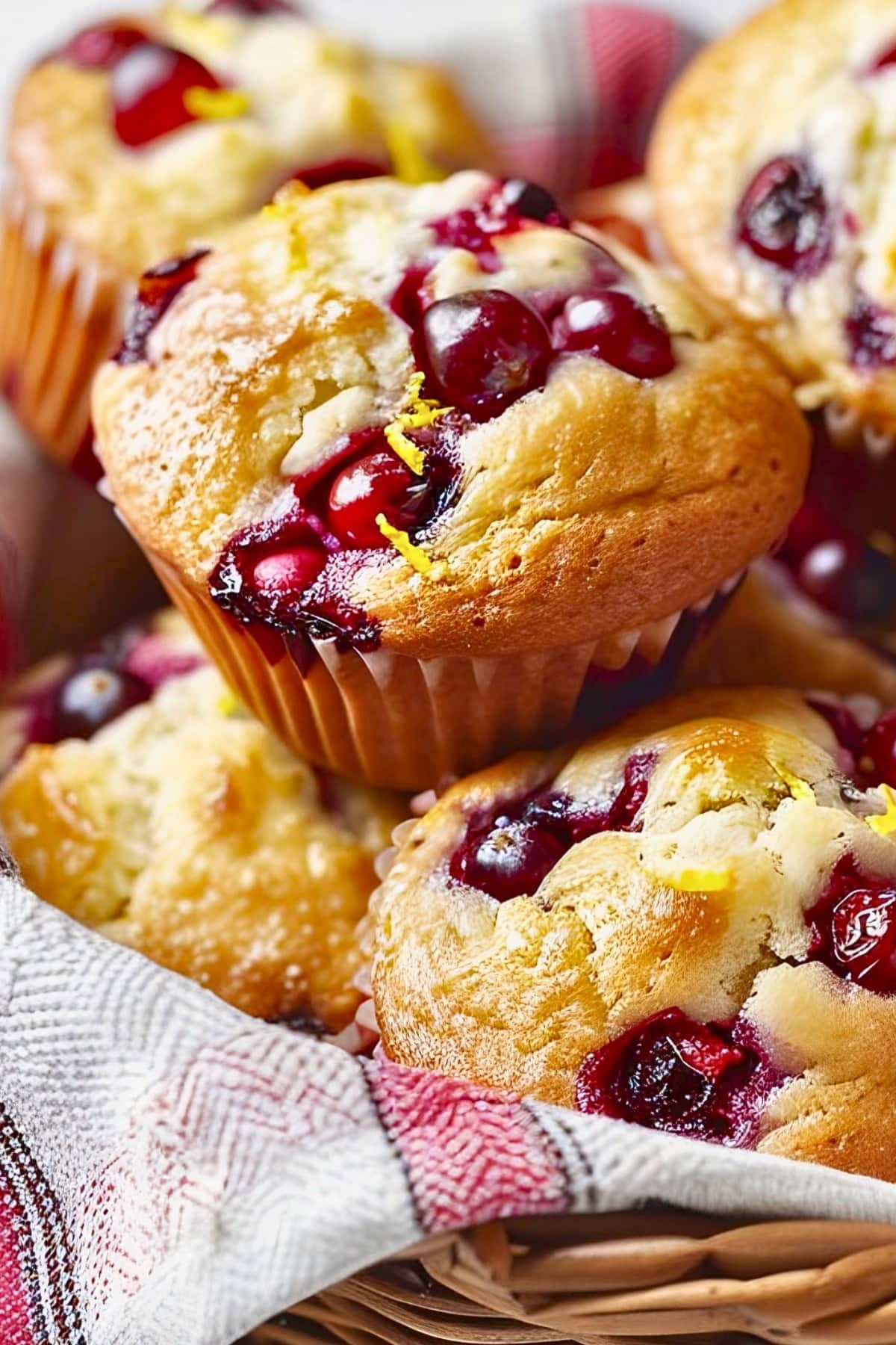 Super Close Up of Cranberry Orange Muffins in a Basket with a Red Plaid Kitchen Towel