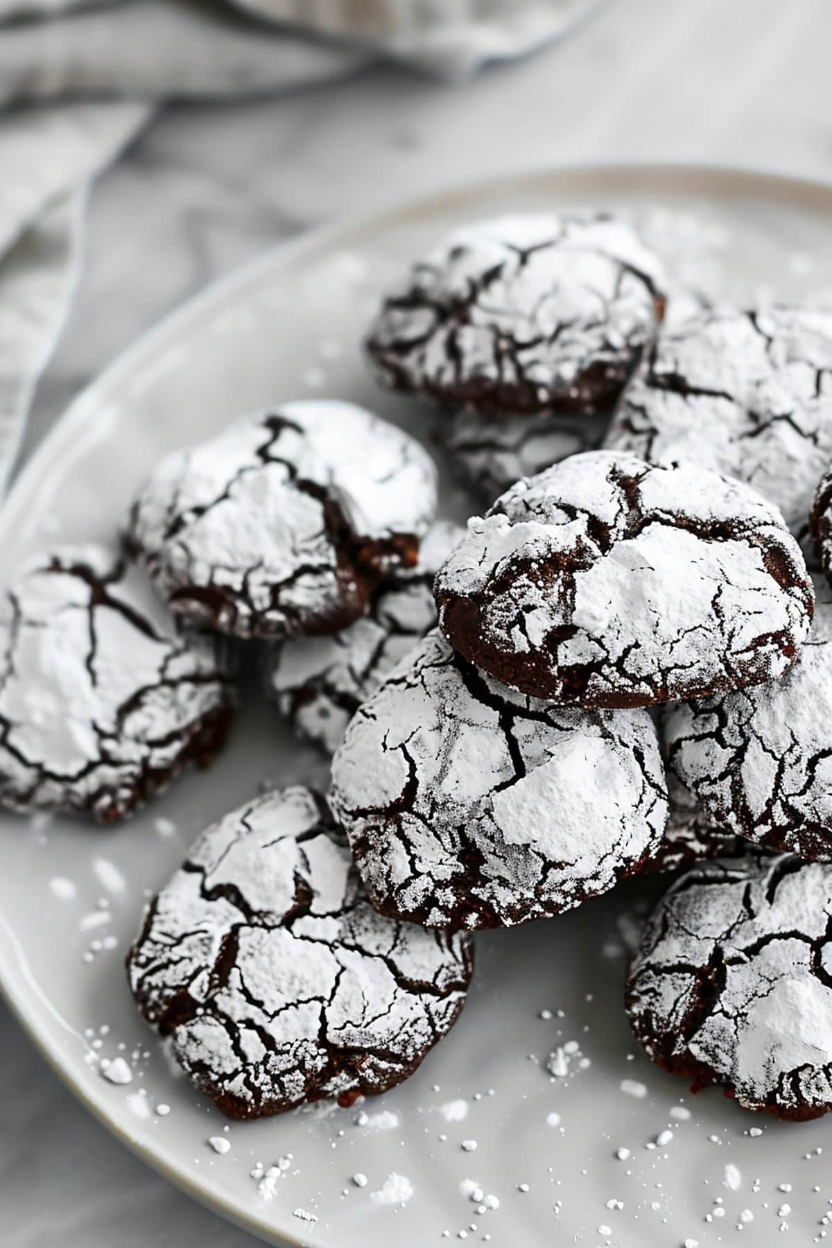 Plate of Fudge Crinkle Cookies, Dusted with Powdered Sugar on a White Plate