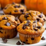 Pumpkin Chocolate Chip Muffins on a Plate with Fresh Pumpkins in the Background