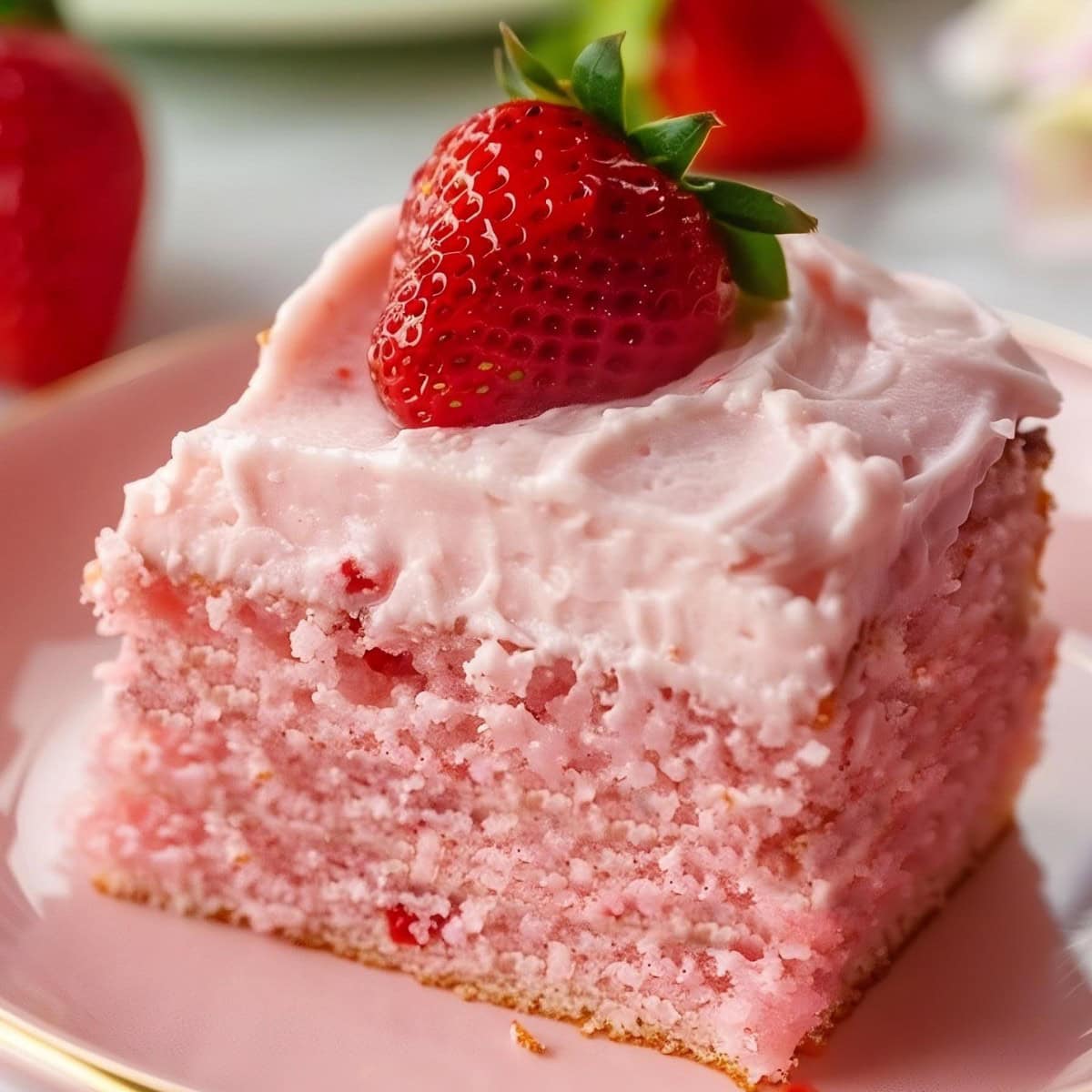 Sliced strawberry sheet cake, covered in fluffy pink icing.