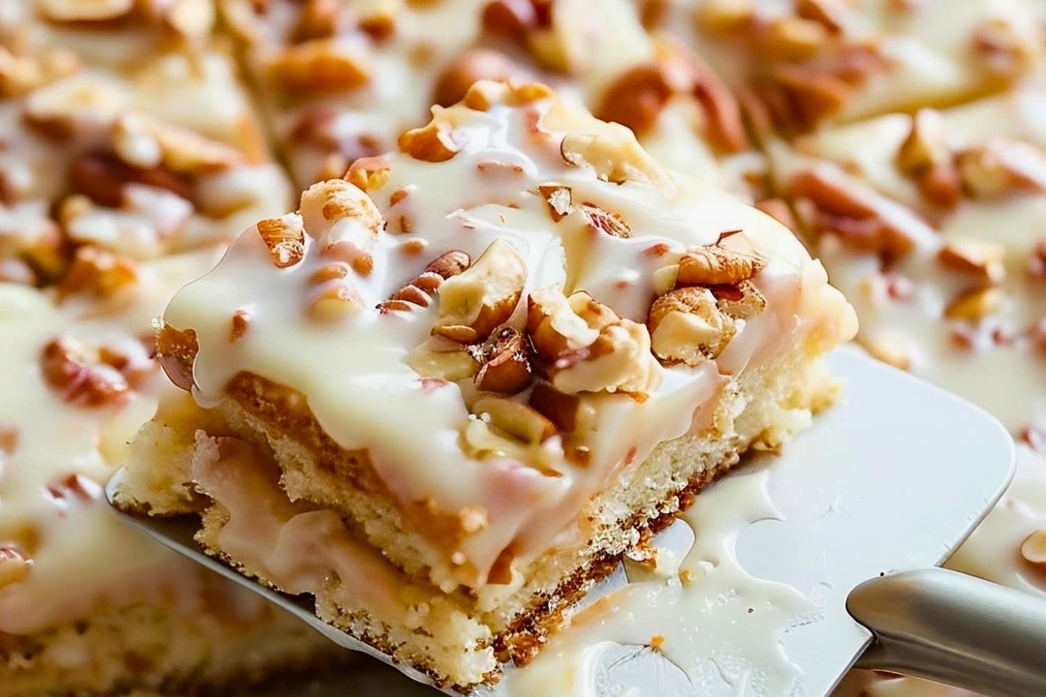 Slice of White Texas Sheet Cake with Pecans on a Spatula