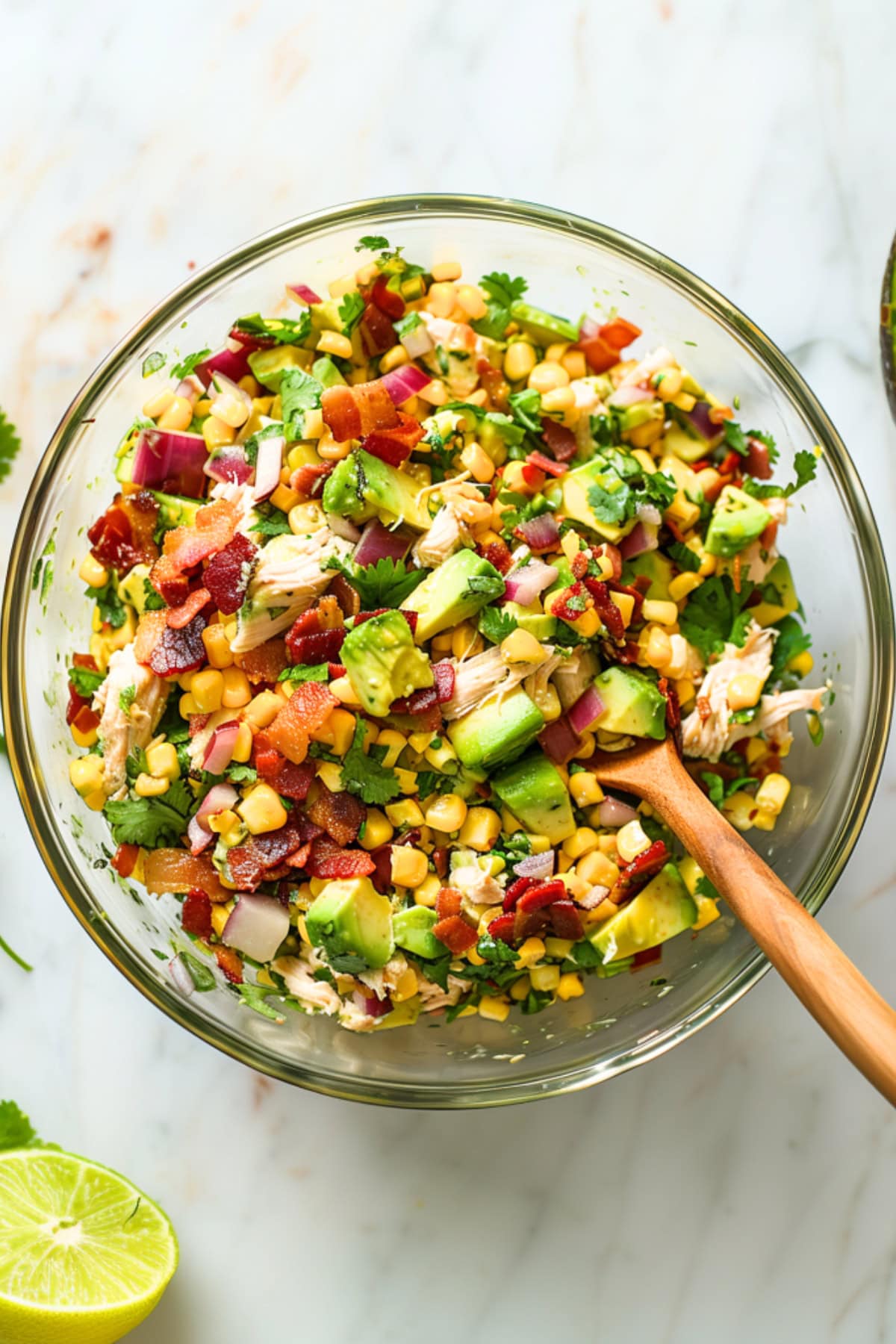 Avocado chicken salad in a glass mixing bowl, top down view