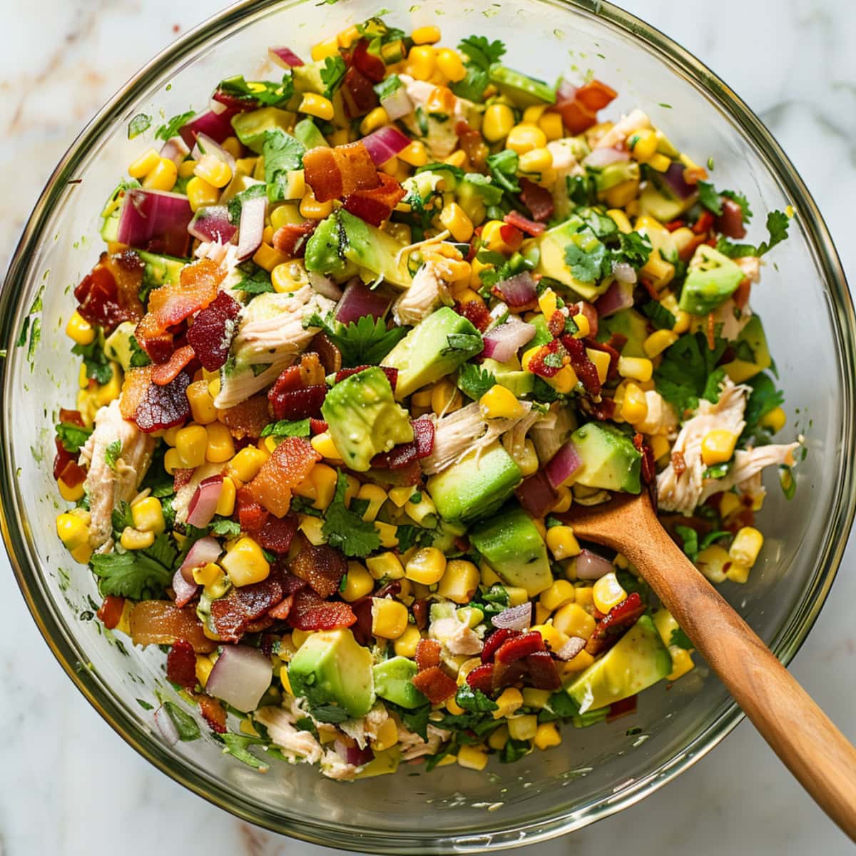 Top view of chicken avocado salad tossed in a glass bowl.