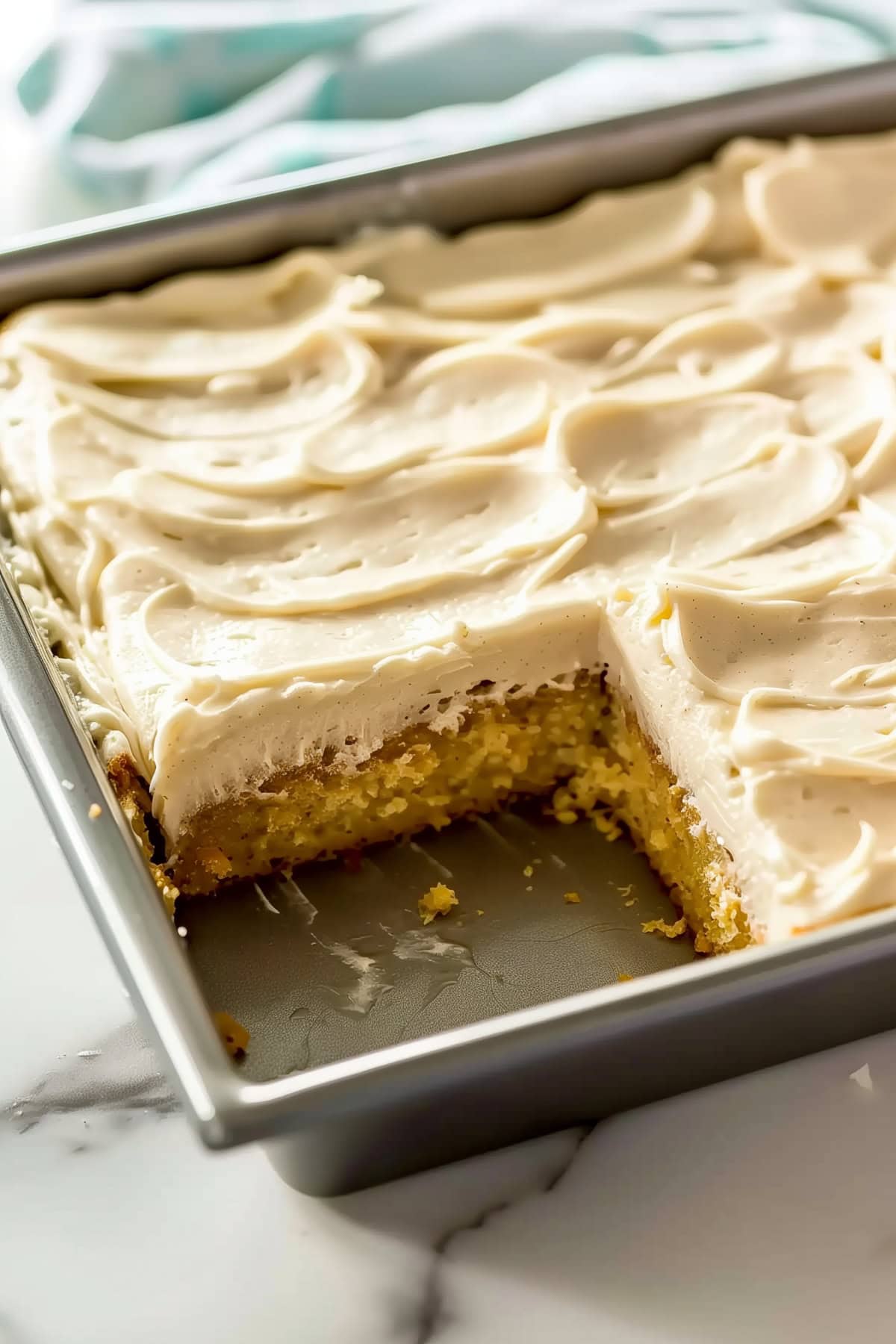 A 9x13-inch Baking Pan Filled with Banana cake topped with Cream Cheese Frosting, a slice removed.