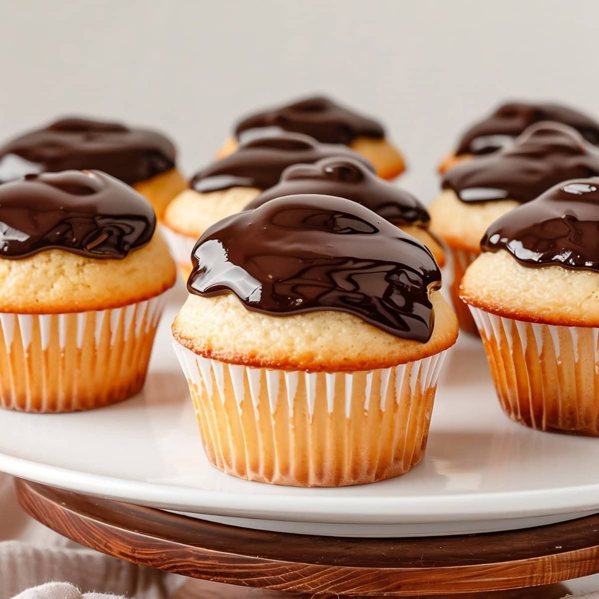 Bunch of Boston cream pie cupcakes arranged in a white plate.