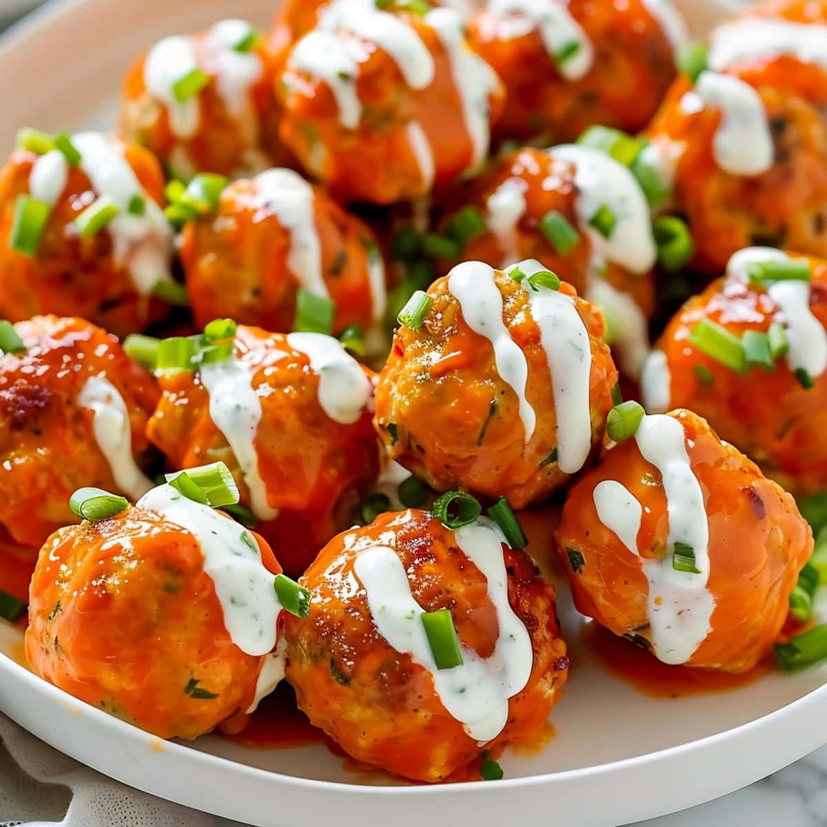 Tasty and spicy buffalo chicken meatballs drizzled with bleu cheese dip and garnished with chopped chives.