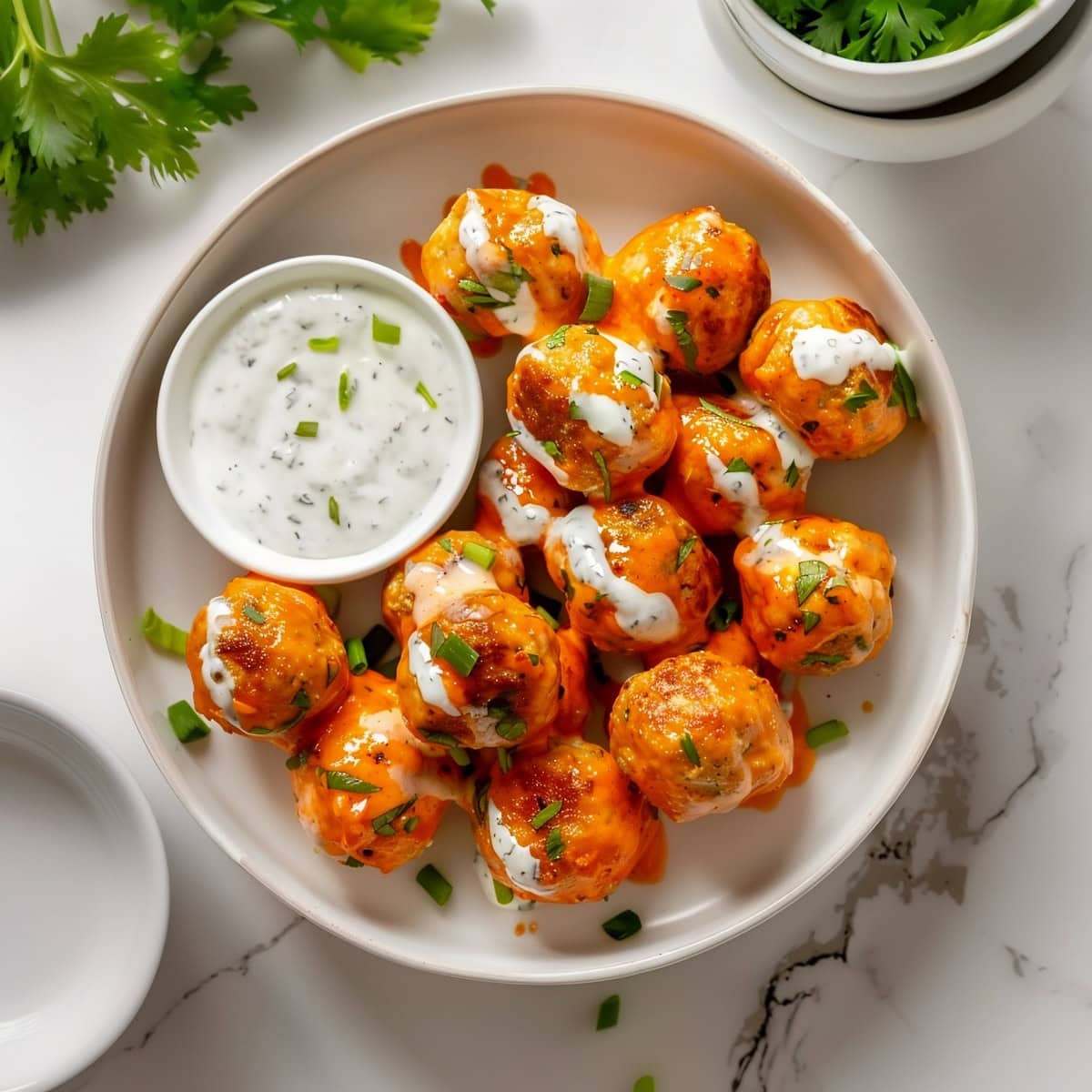 Homemade buffalo chicken meatballs in a white bowl with blue cheese dressing, top down view