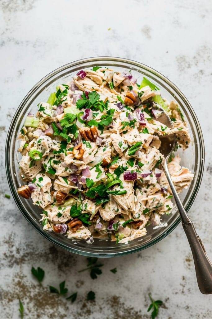 Chicken salad tossed in a glass bowl.