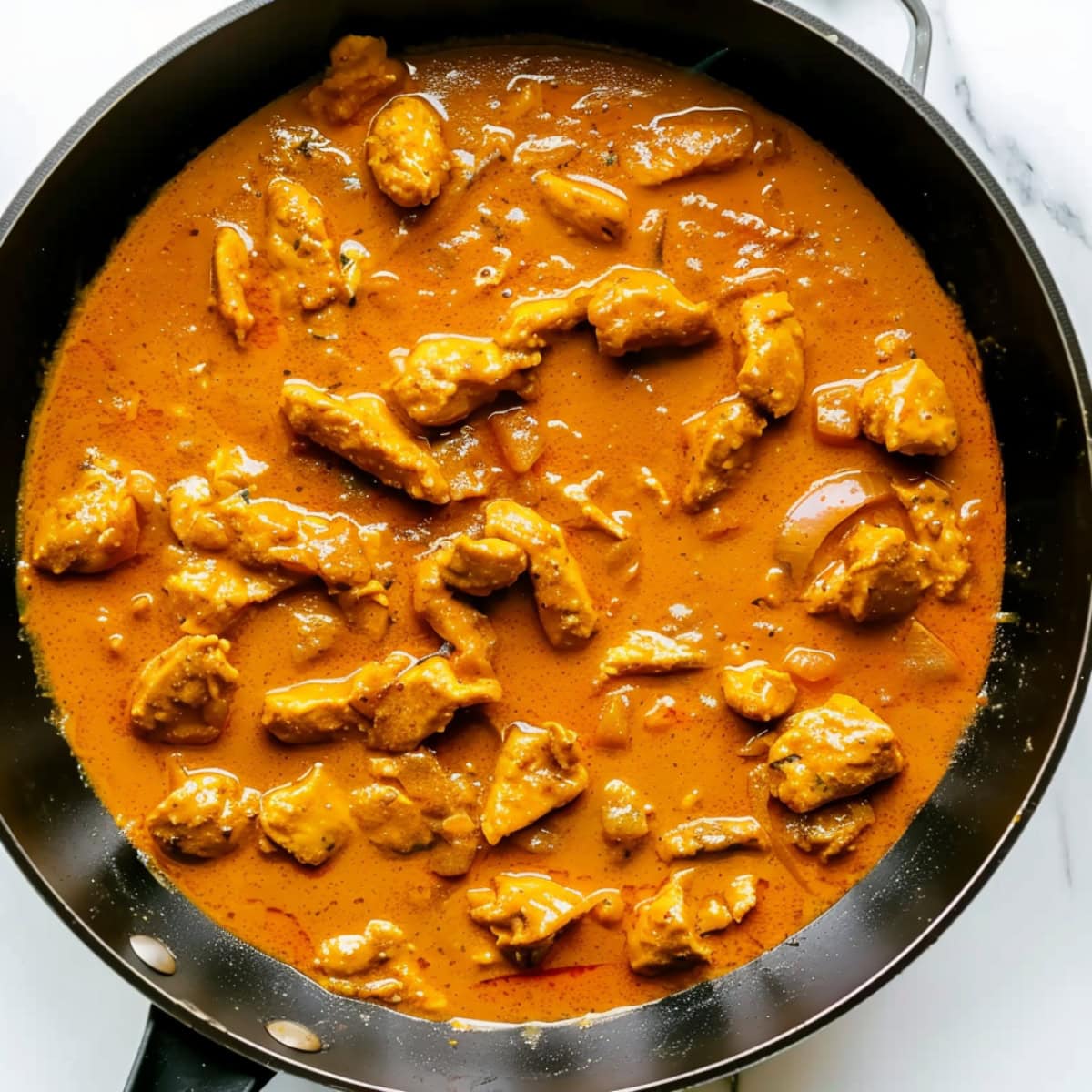 Spicy and Creamy Coconut Chicken Curry in a Deep Black Skillet, top down view.