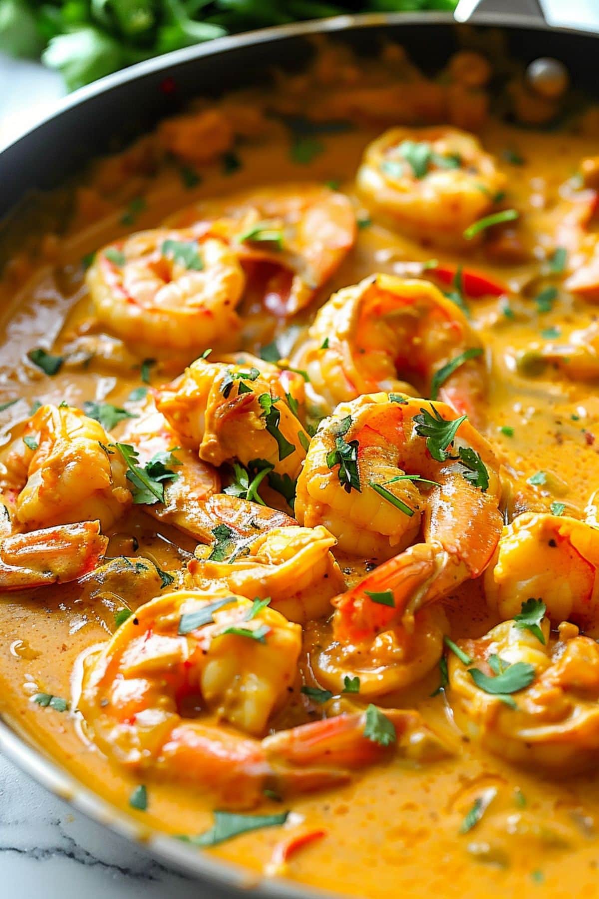 Shrimp cooked in creamy coconut curry sauce in a wok pan.