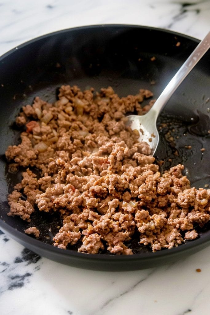 A black skillet filled with cooked ground beef.