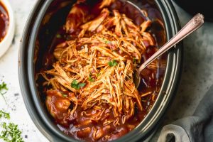 Shredded chicken in bbq sauce inside slow cooker.