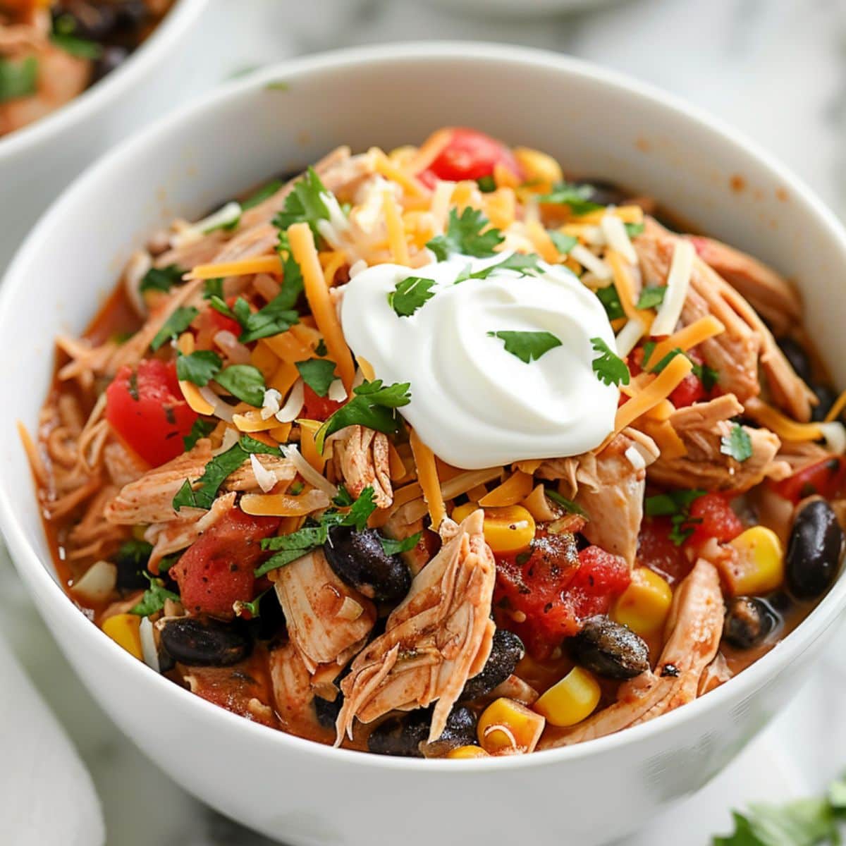 Crockpot chicken tacos served in a white bowl garnished with sour cream.