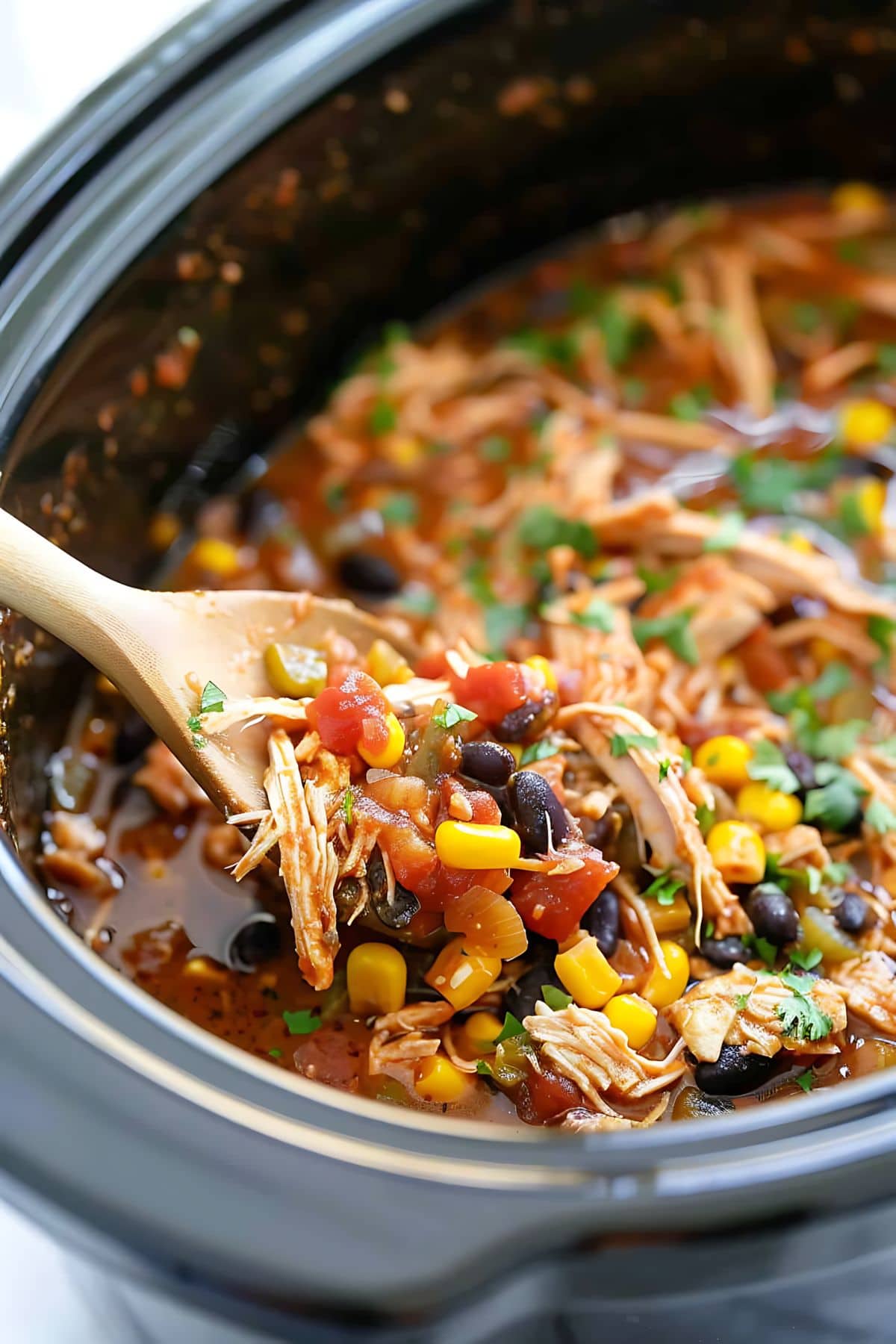 Chicken tacos in a Crockpot tossed with a wooden ladle.