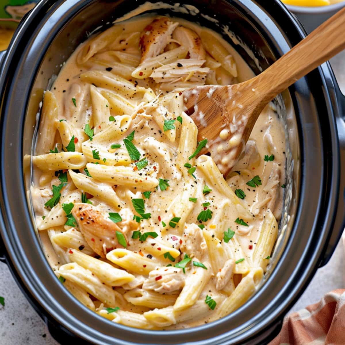 Penne pasta cooked in creamy Olive Garden sauce with shredded chicken in a slow cooker.