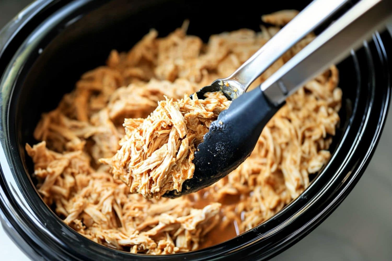 Shredded chicken cooked in a slow cooker crockpot.