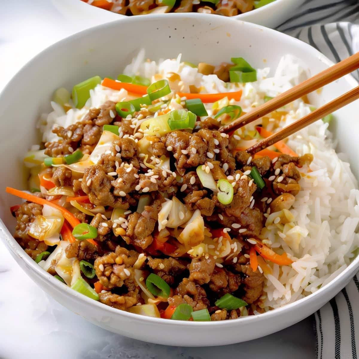 Flavorful egg roll in a bowl topped with green onions and sesame seeds.