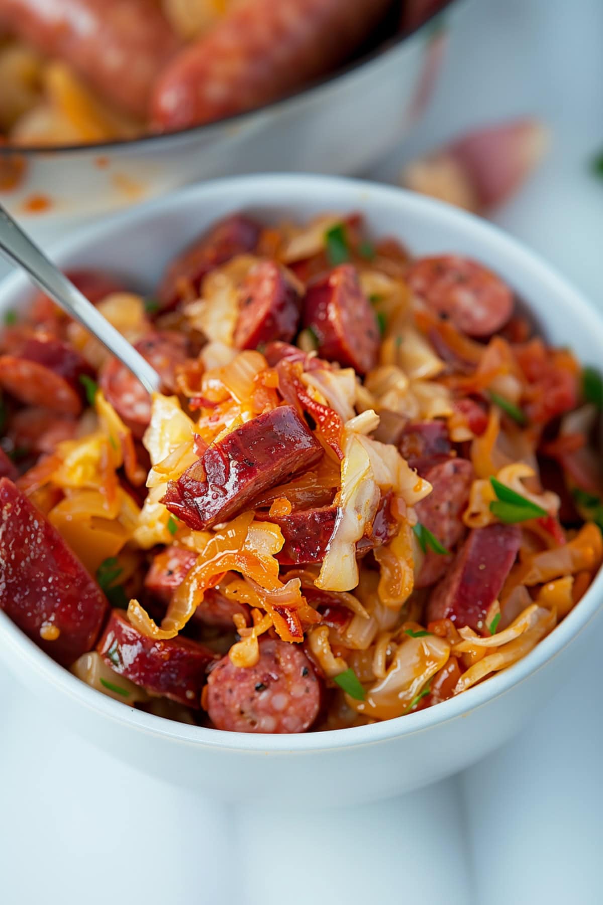 Bowl of tender cabbage and sausage with paprika.