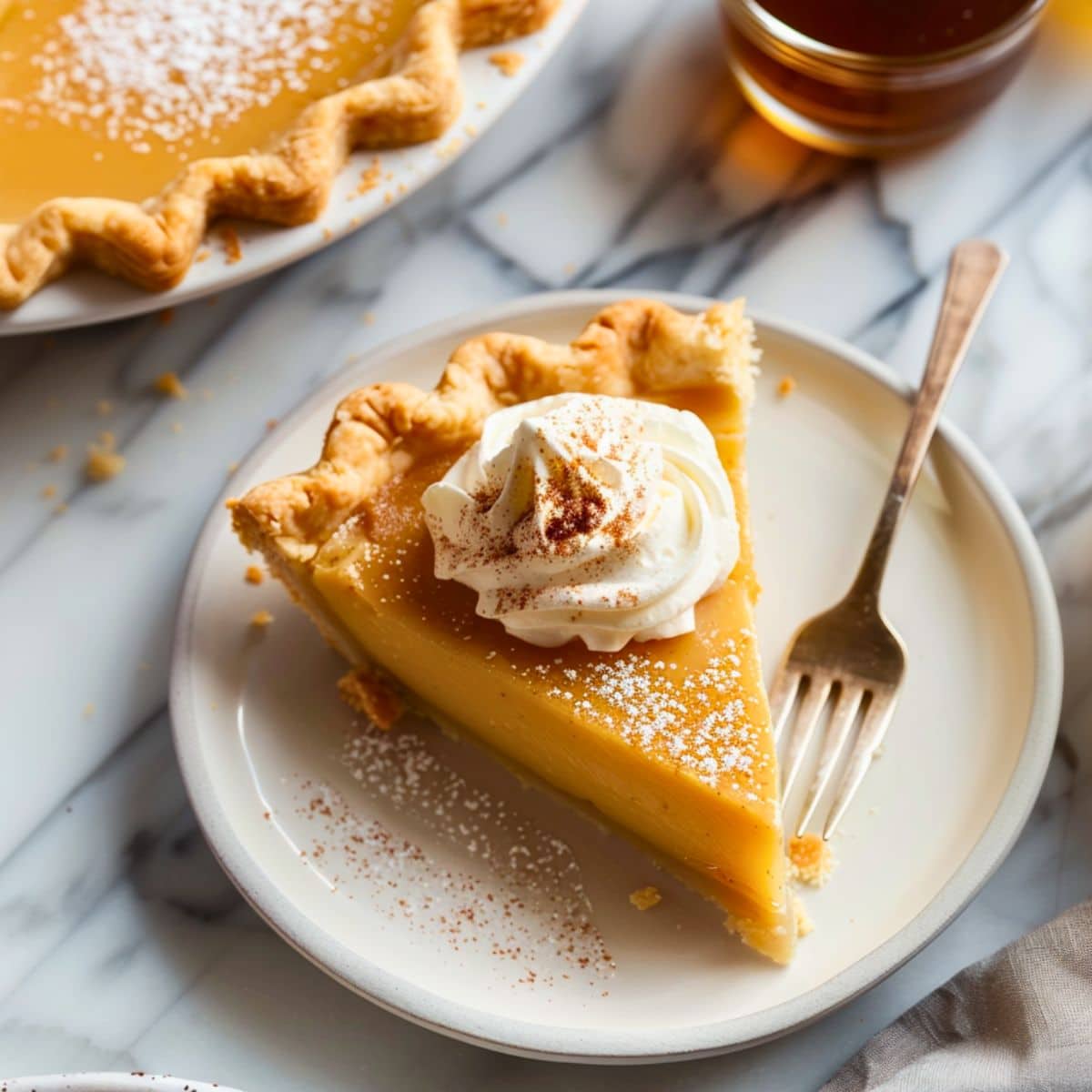 Slice pf maple cream pie on a white plate garnished with whipped cream.