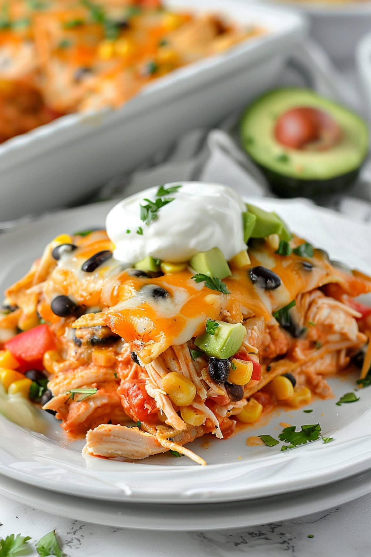 Mexican chicken casserole with avocado and sour cream on top.