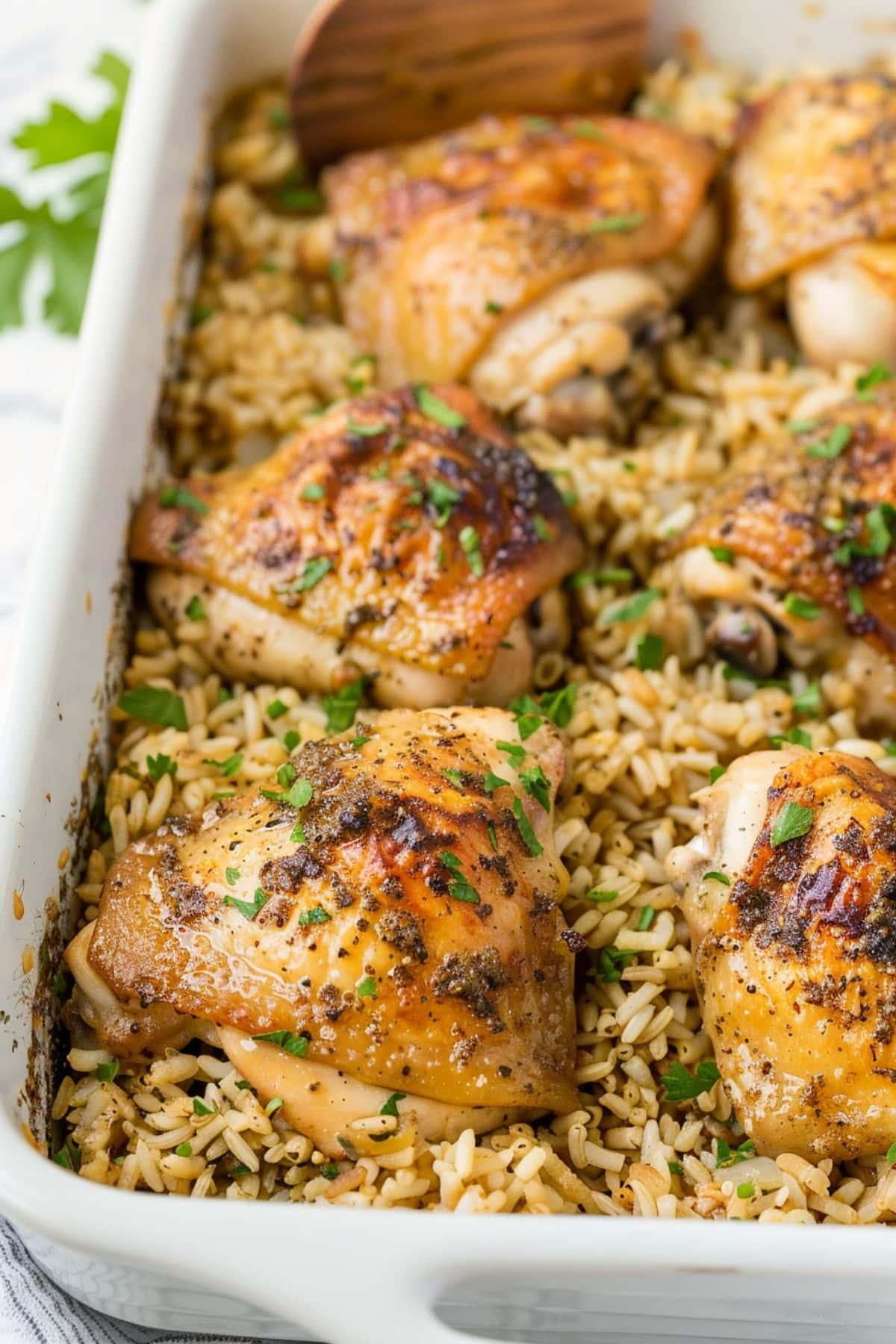 Oven baked chicken and rice on a white baking dish.