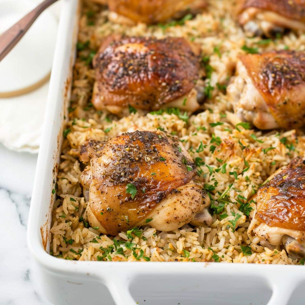 Chicken and seasoned rice baked on a white rectangular baking dish.