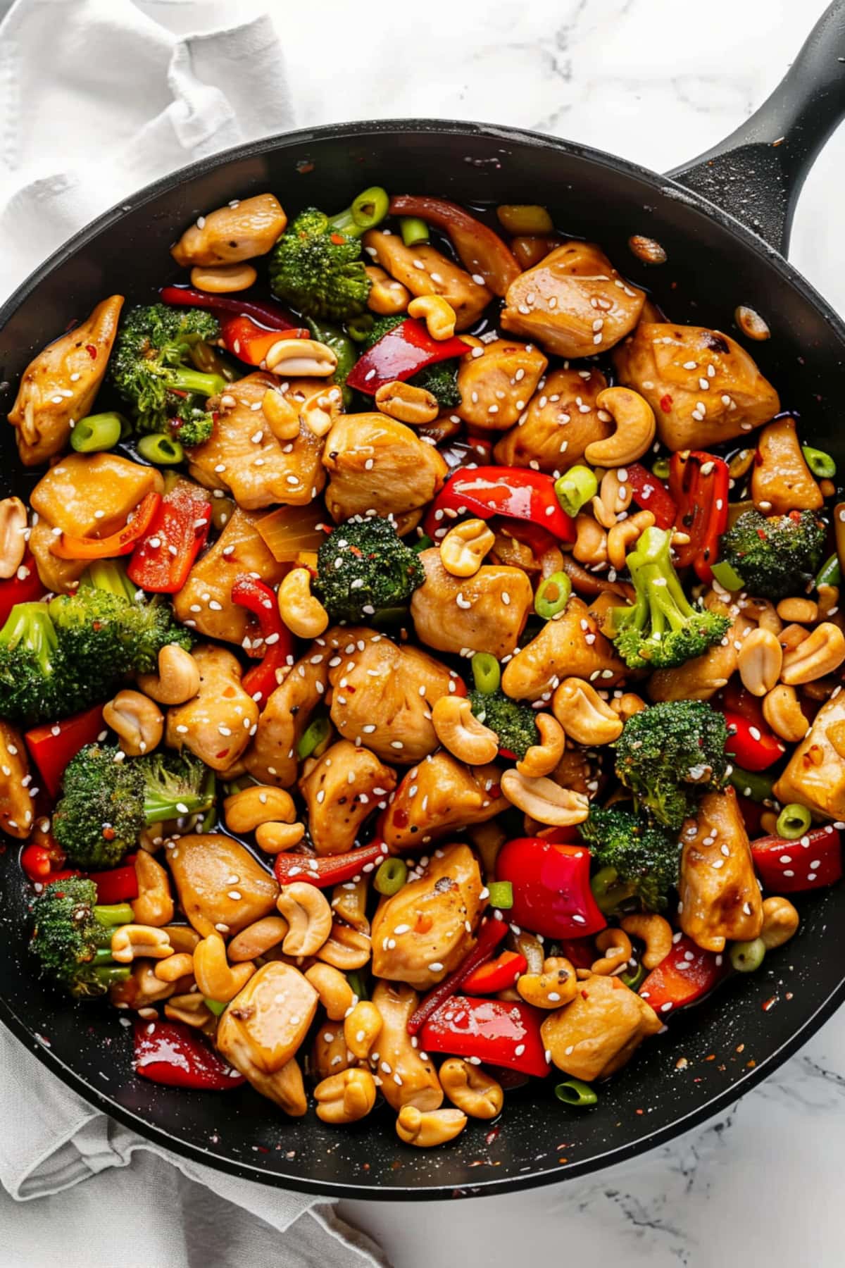 Teriyaki chicken stir-fry with broccoli, cashew, red bell peppers and green onions, top view.