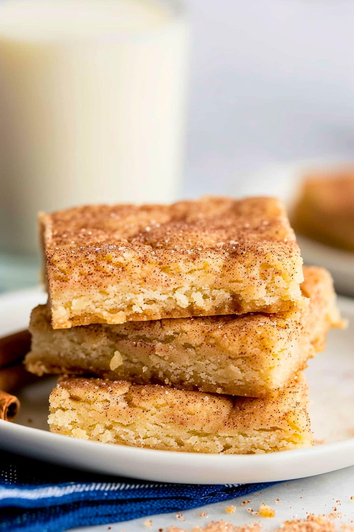 Square slices of snickerdoodle bars stacked on a white plate.