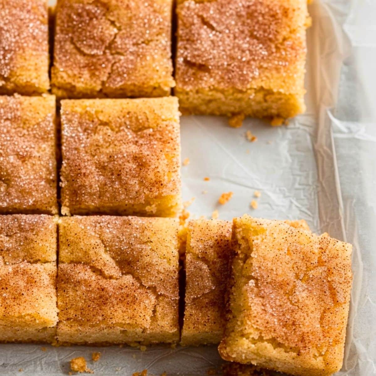 Soft and chewy snickerdoodle bars sliced on a parchment paper.