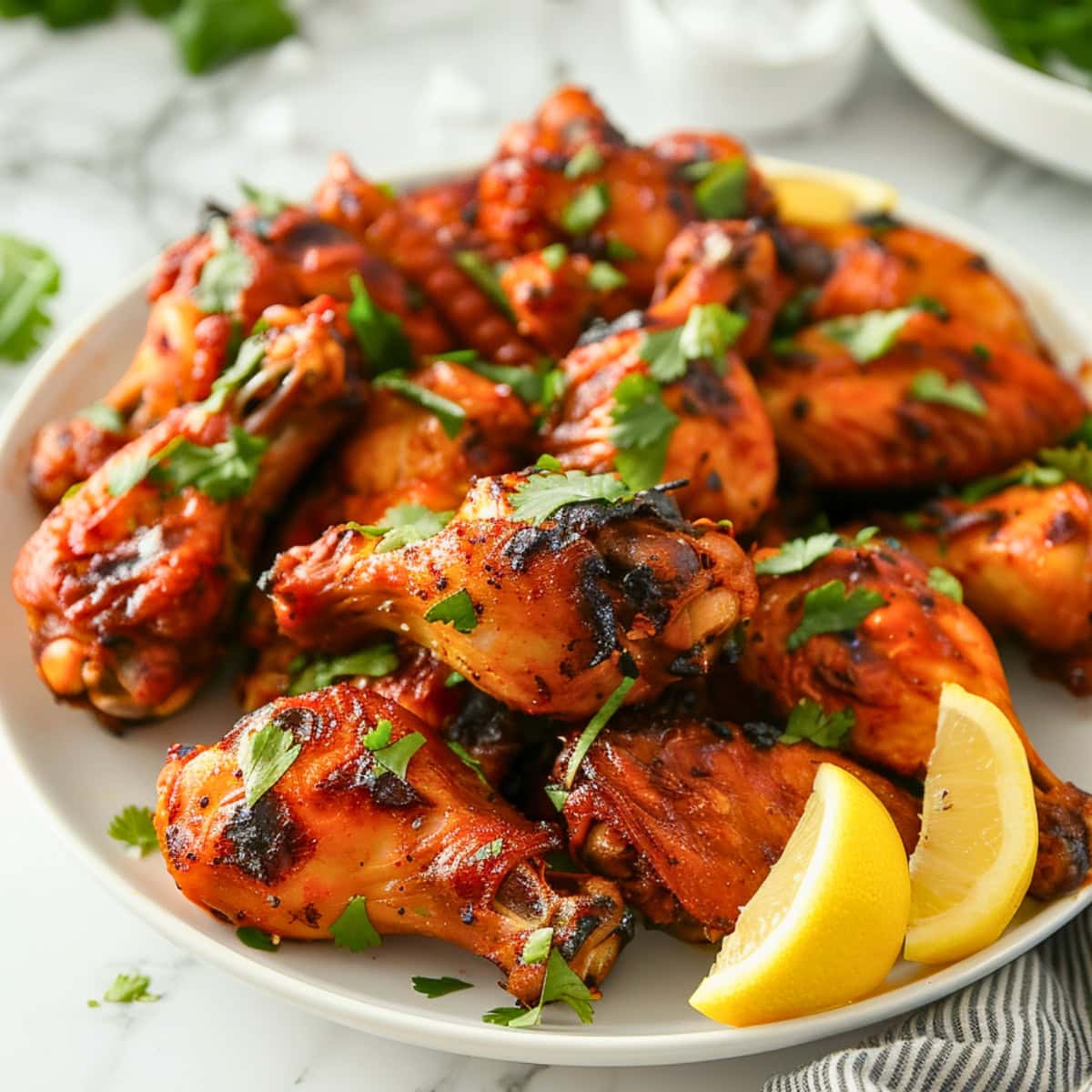 Plate of oven baked tandoori chicken wings the slice of lemons on the side.